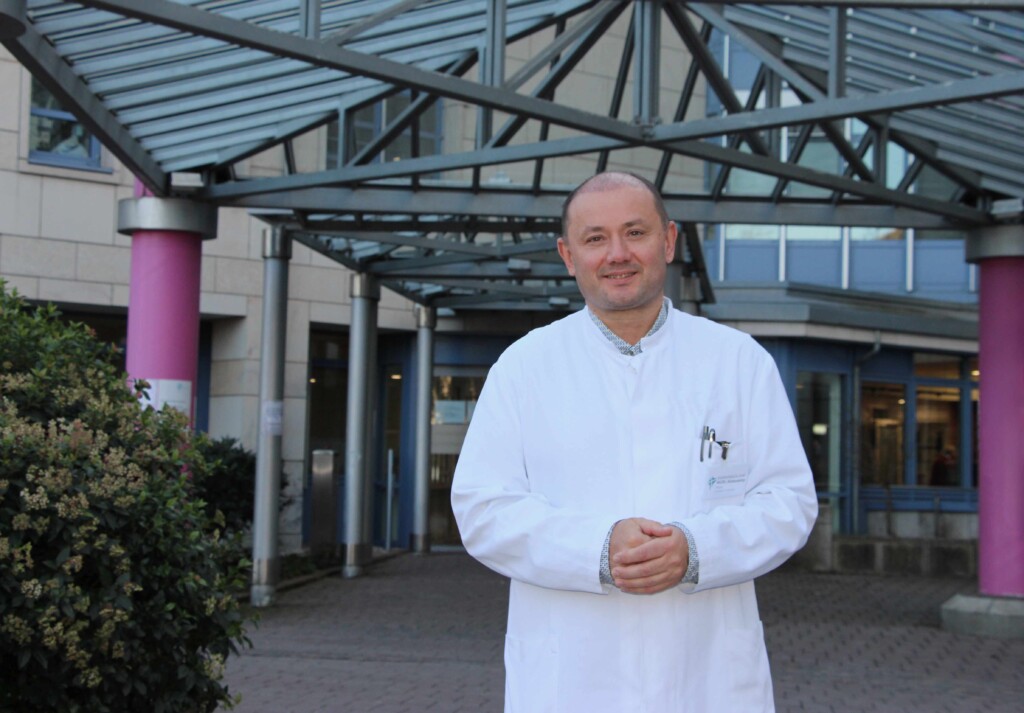 Mann lächelnd vor Gebäude.